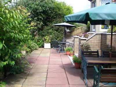a patio with a table and benches and an umbrella at Sunnyside B&B in Balloch