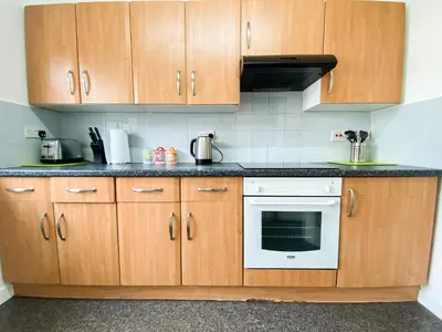 a kitchen with wooden cabinets and a white oven at Glasgow Green Park Home in Glasgow
