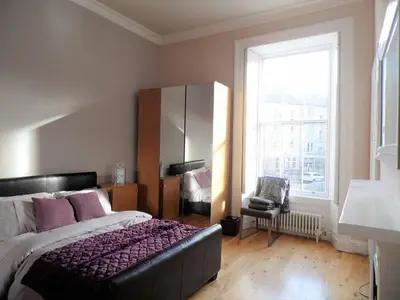a bedroom with a bed and a large window at WEST END - Stunning, spacious, 3 bedroom, main door flat with private parking in Glasgow