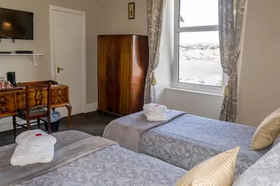 a room with two beds and a desk and a window at The Tregortha B&B in Tighnabruaich