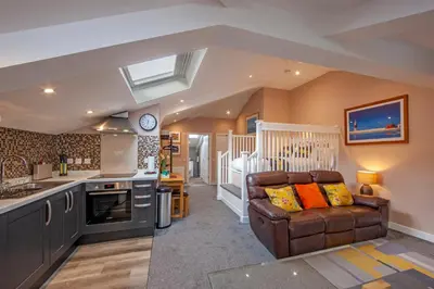 a kitchen and a living room with a couch at Mandarin Premier Apartments B - Loft studio apt in Oban