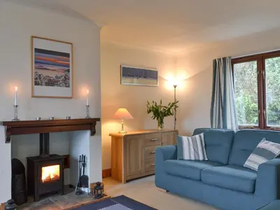 a living room with a blue couch and a fireplace at Tigh An Aighear in Arduaine