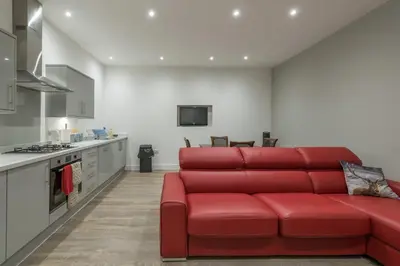 a living room with a red couch in a kitchen at Haymarket Spacious 3 Bedroom Street Level in Edinburgh
