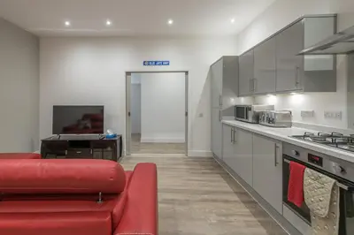a living room with a red couch in a kitchen at Haymarket Spacious 3 Bedroom Street Level in Edinburgh