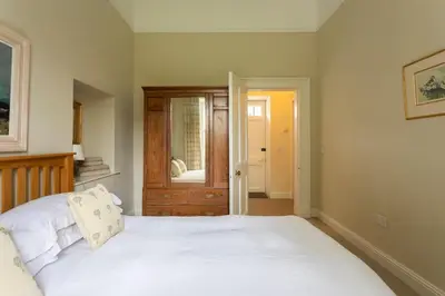 a bedroom with a white bed and a mirror at Old Leckie Farmstay in Stirling
