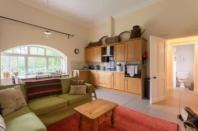 a living room with a couch and a kitchen at Old Leckie Farmstay in Stirling