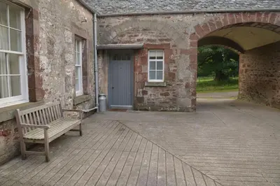 a wooden bench sitting outside of a brick building with a door at Old Leckie Farmstay in Stirling