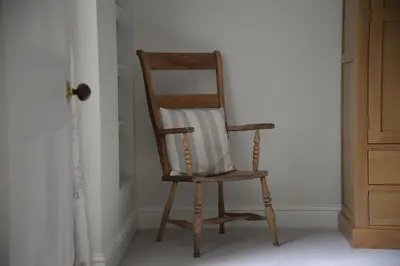 a wooden chair with a pillow sitting in a room at Old Leckie Farmstay in Stirling