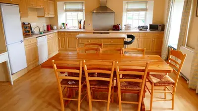 a kitchen with a wooden table and wooden chairs at Arndean Cottages in Dollar