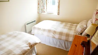 a small bedroom with two beds and a window at Arndean Cottages in Dollar