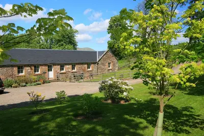 a stone building with a courtyard in front of it at Arndean Cottages in Dollar
