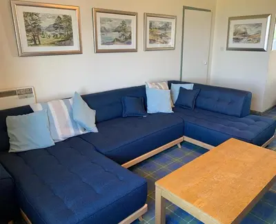 a living room with a blue couch and a table at Beach Front Flat, Brodick in Brodick