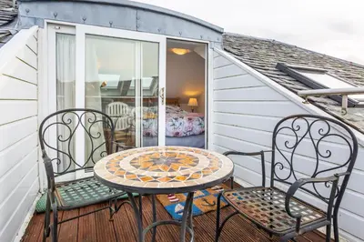 a patio with a table and chairs on a balcony at Beach Front Flat, Brodick in Brodick