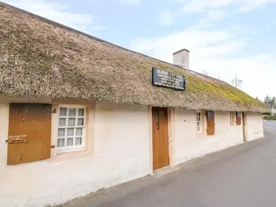 a building with a grass roof with a sign on it at Bright and Beautiful in Ayr