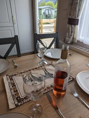 a table with a bottle of whiskey and a glass at Swift Bordeaux Sea View 15 in Dunoon