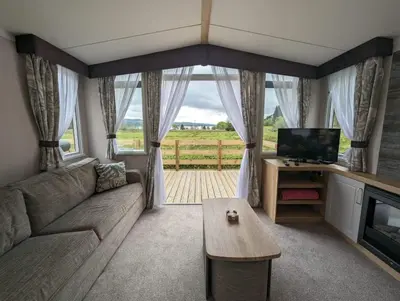a living room with a couch and a tv and a table at Swift Bordeaux Sea View 15 in Dunoon