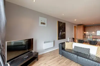 a living room with a couch and a flat screen tv at Modern Riverfront Apt. 10 mins from Hydro/SECC in Glasgow