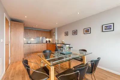 a dining room with a glass table and chairs at Modern Riverfront Apt. 10 mins from Hydro/SECC in Glasgow