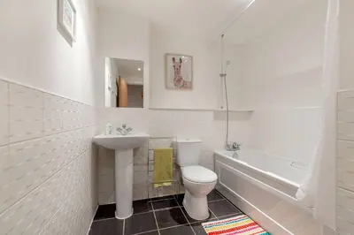 a white bathroom with a sink and a toilet and a tub at Modern Riverfront Apt. 10 mins from Hydro/SECC in Glasgow