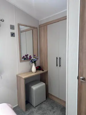 a bedroom with a table with a mirror and a vase with flowers at The Manor Sea View 1A in Ardentinny