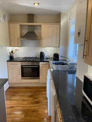 a kitchen with black counter tops and wooden cabinets at Dumbarton With A View in Dumbarton