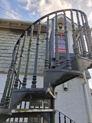a building with a balcony with a pink window at Black Stair Room - En Suite in Helensburgh