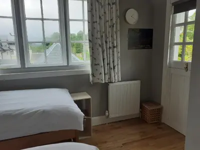 a bedroom with a bed and two windows at Black Stair Room - En Suite in Helensburgh
