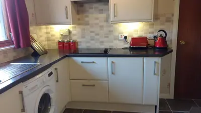 a kitchen with white cabinets and a washing machine at Skerryvore in Oban