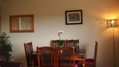 a dining room table with chairs and a table with flowers on it at Skerryvore in Oban