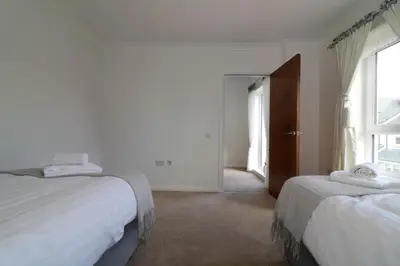 a white bedroom with two beds and a window at Signature - Macneish House East Kilbride in East Kilbride