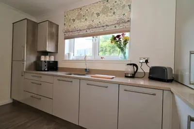 a kitchen with white cabinets and a window at Signature - Macneish House East Kilbride in East Kilbride