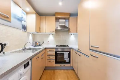 a kitchen with a sink and a stove at Modern 2 bed BroomPark/Central apt. with Parking in Glasgow