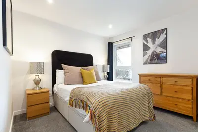 a bedroom with a bed and a dresser and a window at Modern 2 bed BroomPark/Central apt. with Parking in Glasgow