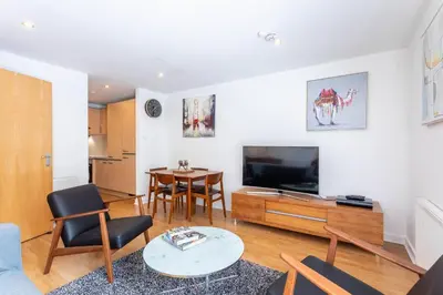 a living room with a television and a table at Modern 2 bed BroomPark/Central apt. with Parking in Glasgow