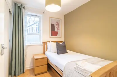 a small bedroom with a bed and a window at Merchant City Glasgow Green Apartment With Parking in Glasgow
