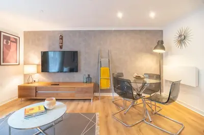 a living room with a tv and a table and chairs at Merchant City Glasgow Green Apartment With Parking in Glasgow