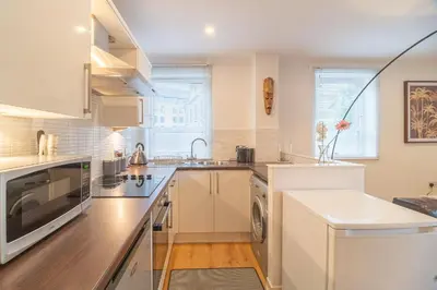 a kitchen with white cabinets and a sink at Merchant City Glasgow Green Apartment With Parking in Glasgow