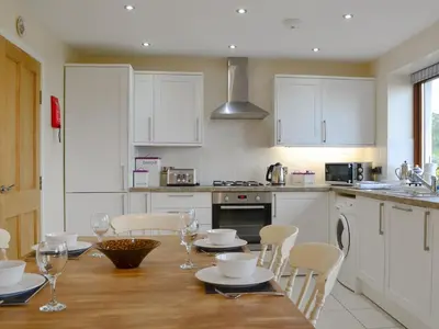 a kitchen with a wooden table and white cabinets at Carribber Beech in Torphichen