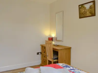 a bedroom with a desk with a chair and a lamp at Carribber Beech in Torphichen