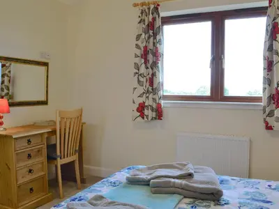 a bedroom with a bed and a desk and a window at Carribber Beech in Torphichen