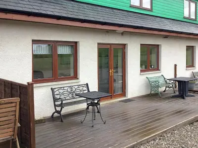 a patio with two tables and a bench next to a house at Carribber Beech in Torphichen