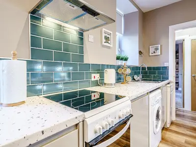 a kitchen with green tiles on the wall at Ivy Cottage in Dunoon