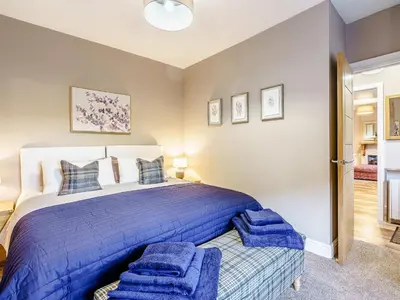 a bedroom with a large bed with blue blankets at Ivy Cottage in Dunoon