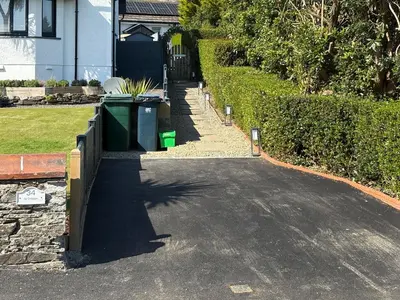 a driveway with two trash cans on the side of a house at Ivy Cottage in Dunoon