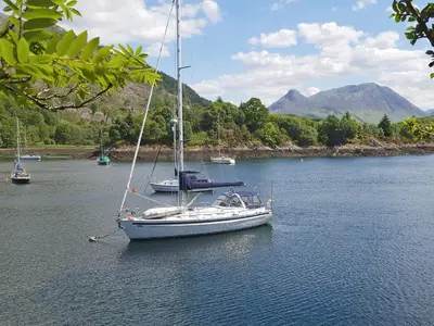 a sailboat in a body of water with other boats at Lismore Cottage in North Ballachulish