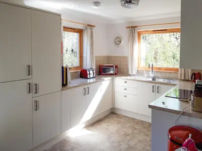 a kitchen with white cabinets and a microwave at Lismore Cottage in North Ballachulish