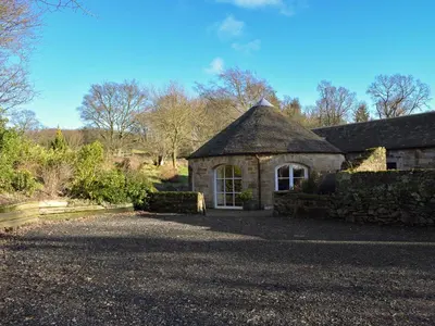 a stone house with a large window in a yard at Horsemill - Uk10794 in Ballingry