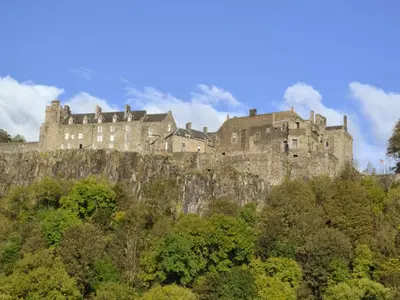 a castle on top of a hill with trees at Bridge End Lodge in Dollar