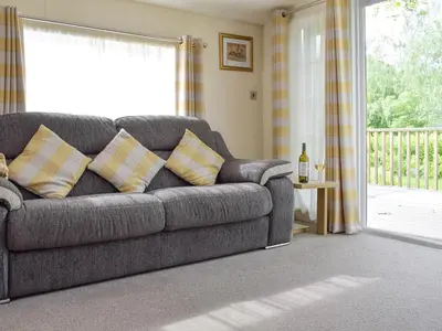 a grey couch in a living room with a window at Bridge End Lodge in Dollar