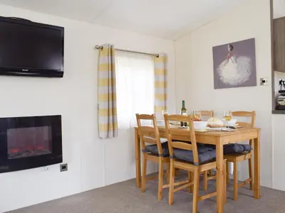 a dining room with a table and chairs and a tv at Bridge End Lodge in Dollar